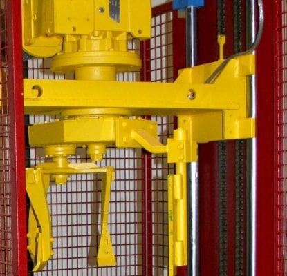 Maquinaria industrial amarilla detrás de una rejilla de seguridad roja en un entorno de fábrica.