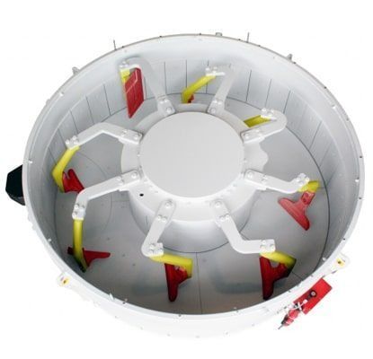 Interior de una máquina industrial con cámara circular blanca, abrazaderas amarillo-rojas y una plataforma redonda central.