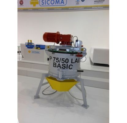Máquina de laboratorio industrial con base blanca, motor rojo y tolva amarilla expuesta en el stand de SICOMA.