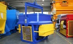 Máquinas de reciclaje industrial de colores vivos en un almacén, con equipos metálicos de color azul, amarillo y rojo.