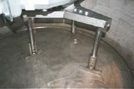 Fregadero o estación de lavado de metal curvado con dos grifos y suelo de baldosas en una habitación con poca luz.
