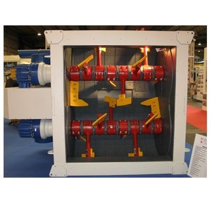 Maquinaria industrial con rodillos giratorios rojos y soportes amarillos dentro de una estructura metálica blanca.