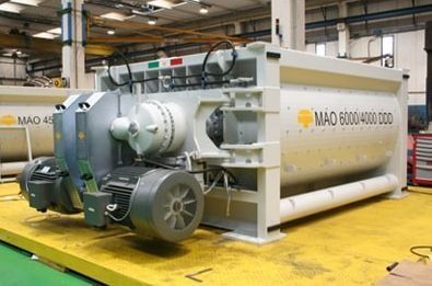 Gran máquina industrial blanca con componentes de motor verdes en un taller de fábrica.