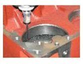 Primer plano de una pieza de máquina roja con un engranaje negro y un perno plateado encima.