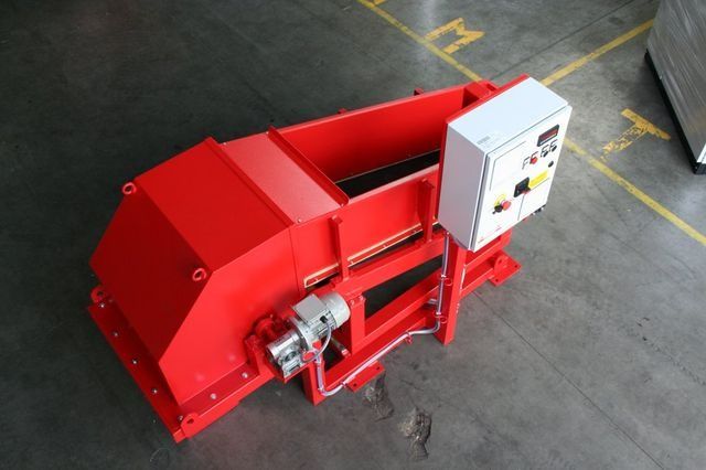 Máquina industrial roja con caja de control blanca en el suelo de una fábrica.