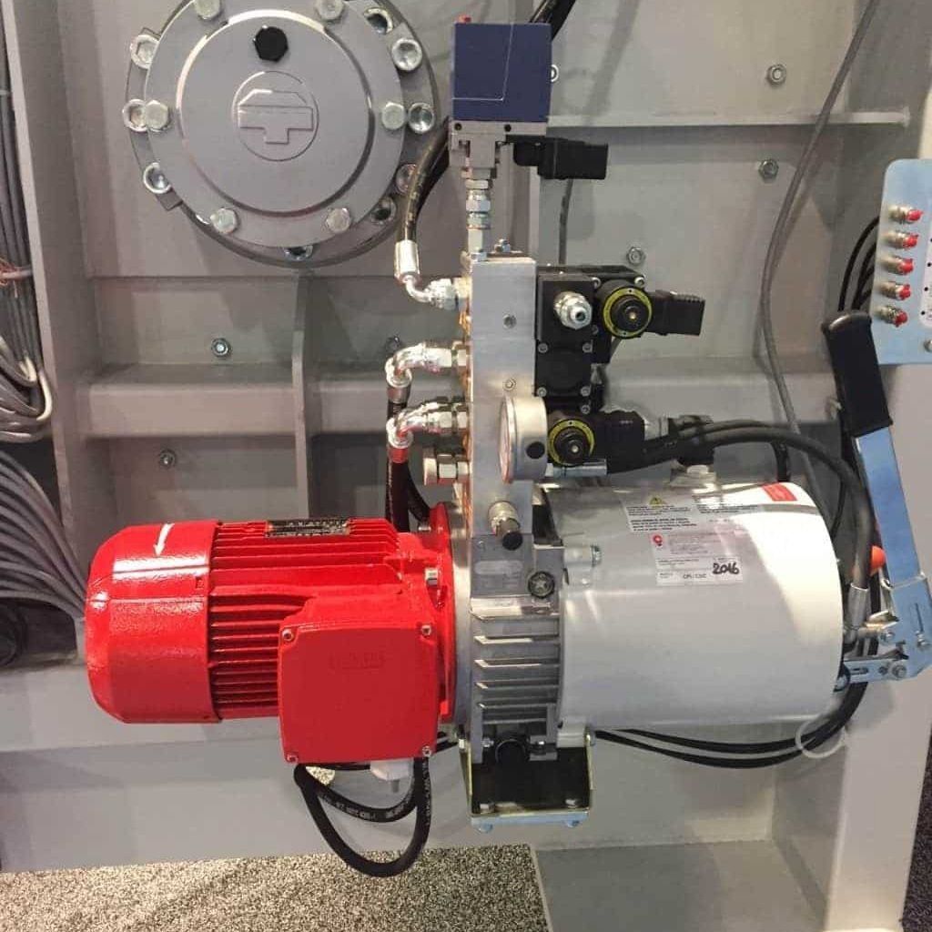 Máquina industrial con conjunto de motor rojo y plateado montado dentro de un armario de control.