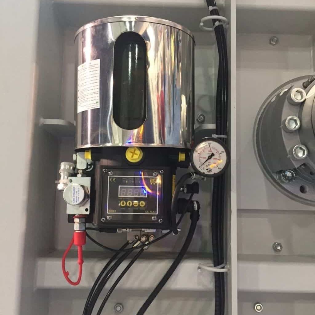 Máquina industrial de acero inoxidable con panel de control, manómetro y mangueras dentro de una carcasa metálica.