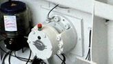 Bomba industrial blanca con depósito de motor negro montada en la pared de un cuarto de servicio.