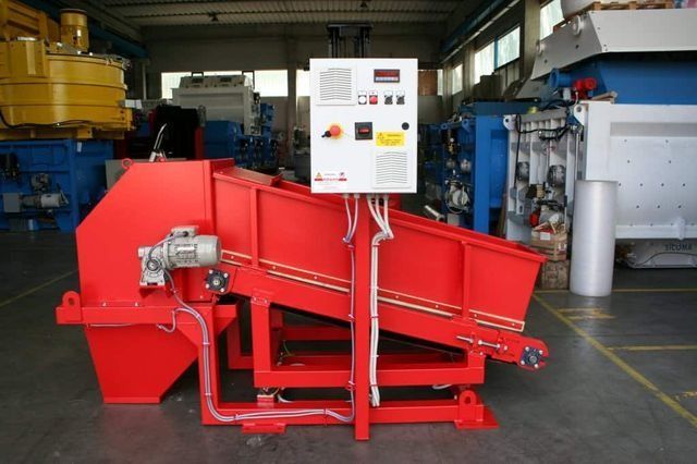 Máquina industrial roja con panel de control blanco en un taller de fábrica.