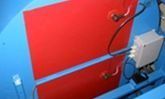 Paneles industriales rojos con cableado y una caja eléctrica montada sobre un bastidor azul.