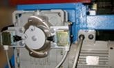 Primer plano de un conjunto mecánico metálico con un componente circular y cableado junto a un motor con aletas.