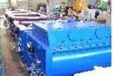 Máquina industrial azul en un taller, con piezas y componentes metálicos a la vista.