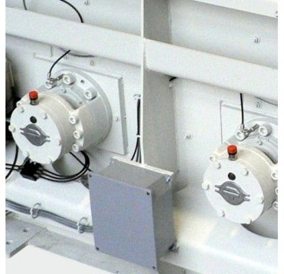 Equipo industrial blanco con dos unidades de válvulas circulares y una caja de control gris dentro de un compartimento de maquinaria.