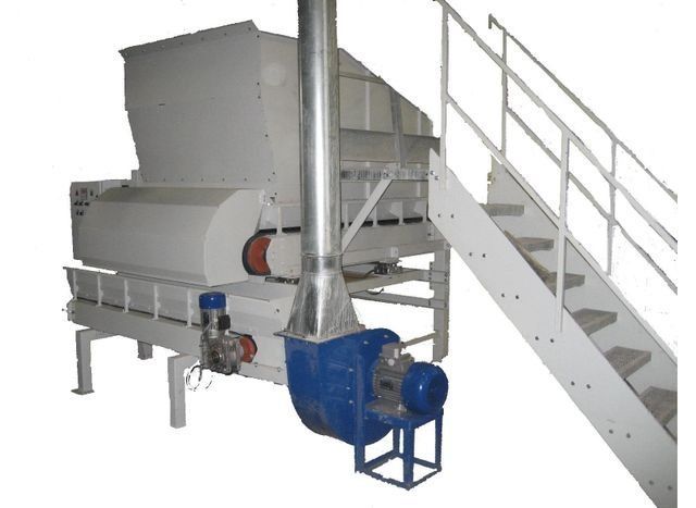 Máquina industrial con motor azul, tolva metálica y escalera adjunta sobre un fondo blanco.