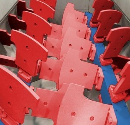 Sillas de plástico rojas y azules dispuestas en filas sobre un suelo de baldosas.