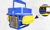 Máquina industrial azul y amarilla con un panel lateral ventilado y una flecha negra que apunta a una vista circular insertada.