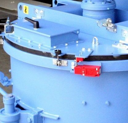 Maquinaria industrial azul con pestillo rojo y abrazaderas metálicas en un tanque cilíndrico.