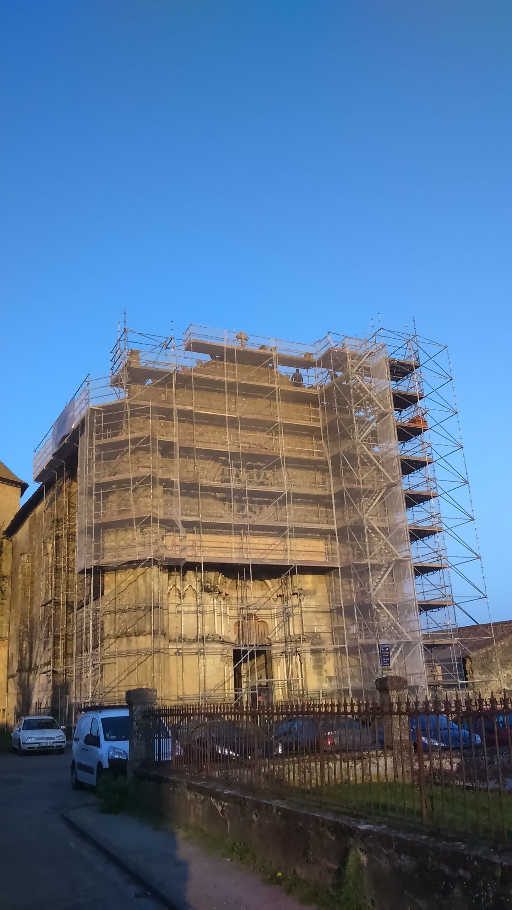 Façade d'un bâtiment en rénovation, recouverte d'échafaudages et de filets.