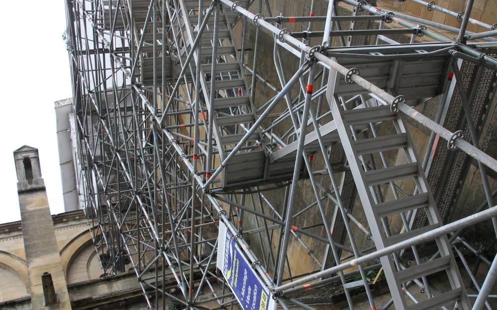 Échafaudage fixé à l'extérieur d'un bâtiment avec plusieurs niveaux d'escaliers et de plateformes.