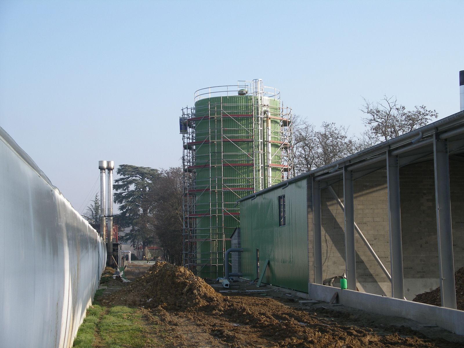 Tour industrielle verte en construction, entourée d'échafaudages.