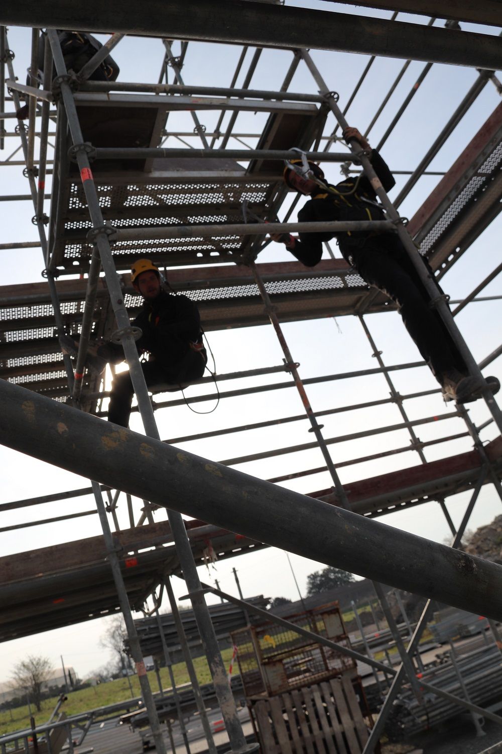 Des ouvriers travaillent sur des échafaudages à la construction d'une charpente de toit. Ils portent des équipements de sécurité.