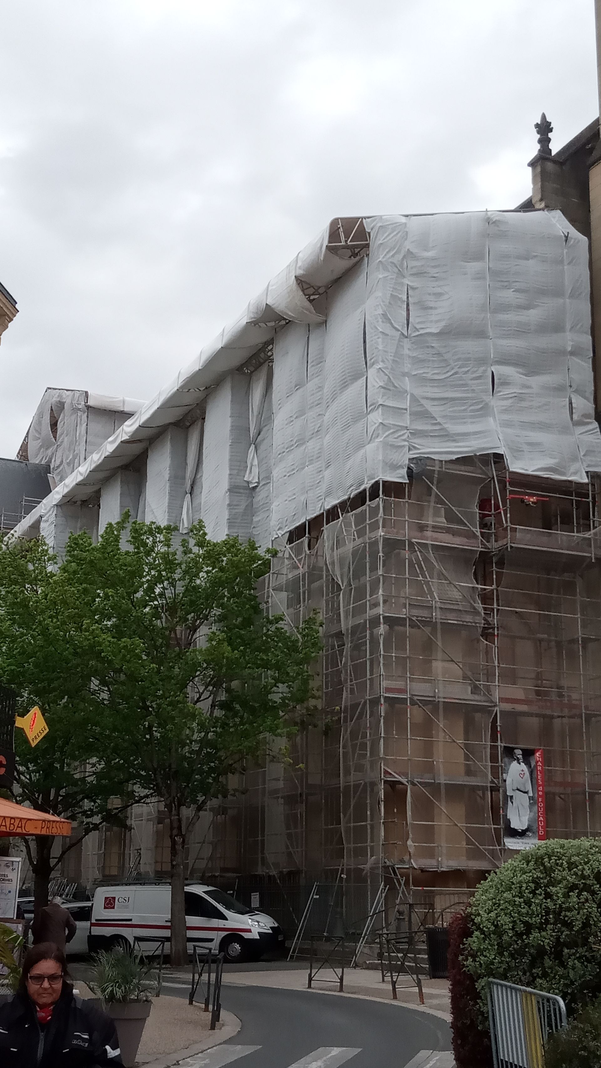 Bâtiment en rénovation, recouvert de bâches blanches et d'échafaudages.