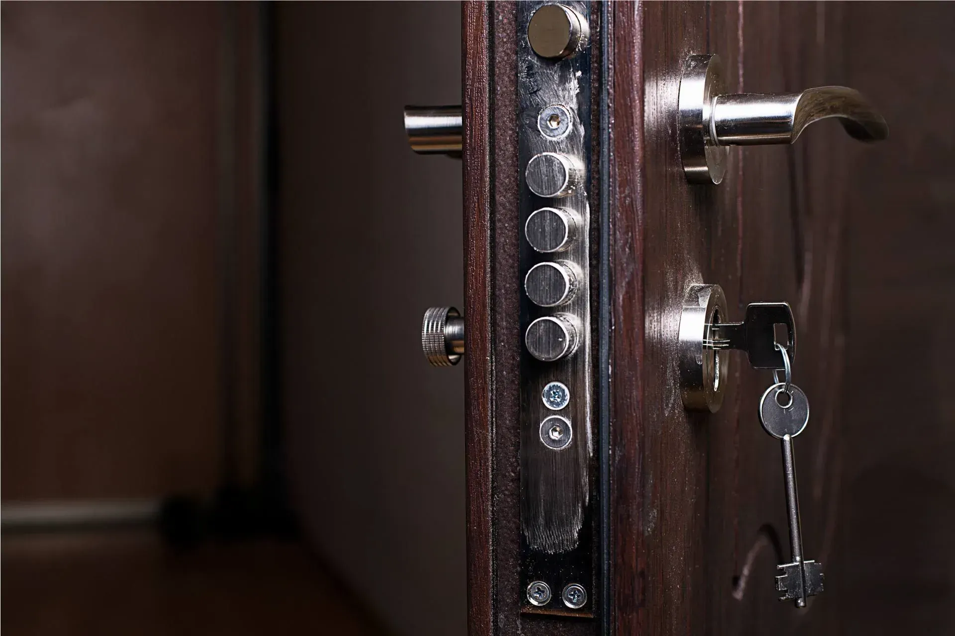 Primer plano de una puerta de madera oscura con una cerradura compleja y una llave en la cerradura.
