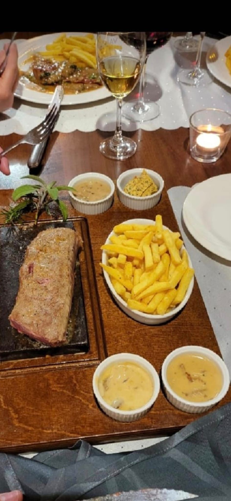 Steak auf einem heissen Stein mit Pommes frites und Dips, gedeckter Restauranttisch.