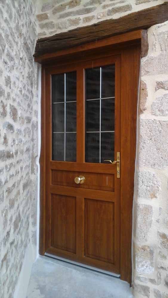 Porte d'entrée en bois avec vitres encastrée dans un mur en pierre