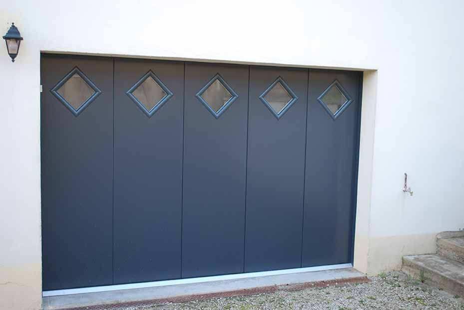 Porte de garage bleu foncé avec fenêtres en losange intégrées à un mur extérieur blanc