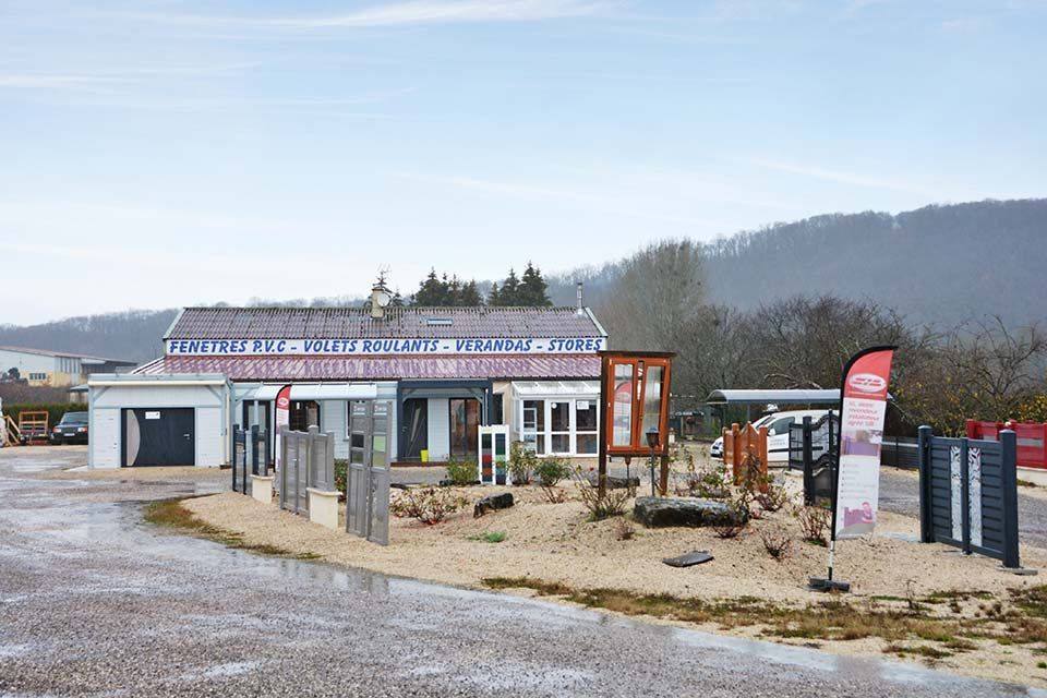 Centre d'accueil touristique en bord de route rurale avec panneaux, parking en gravier et petit bâtiment sous un ciel nuageux