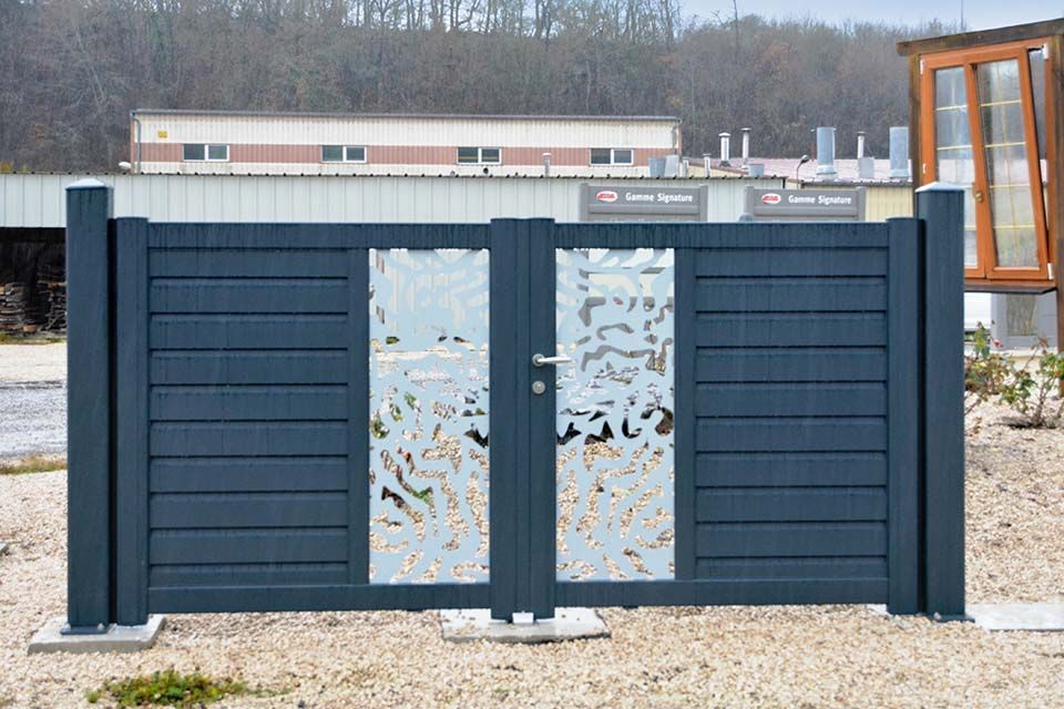 Portail décoratif en métal bleu foncé avec panneaux centraux dépolis dans un terrain extérieur