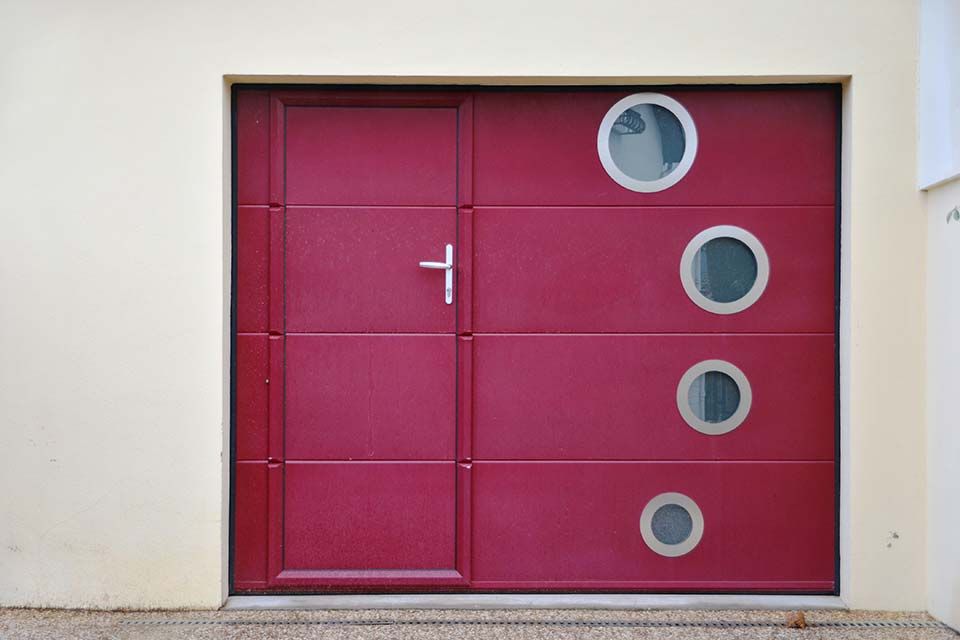 Porte moderne magenta avec quatre hublots circulaires intégrés dans un mur blanc