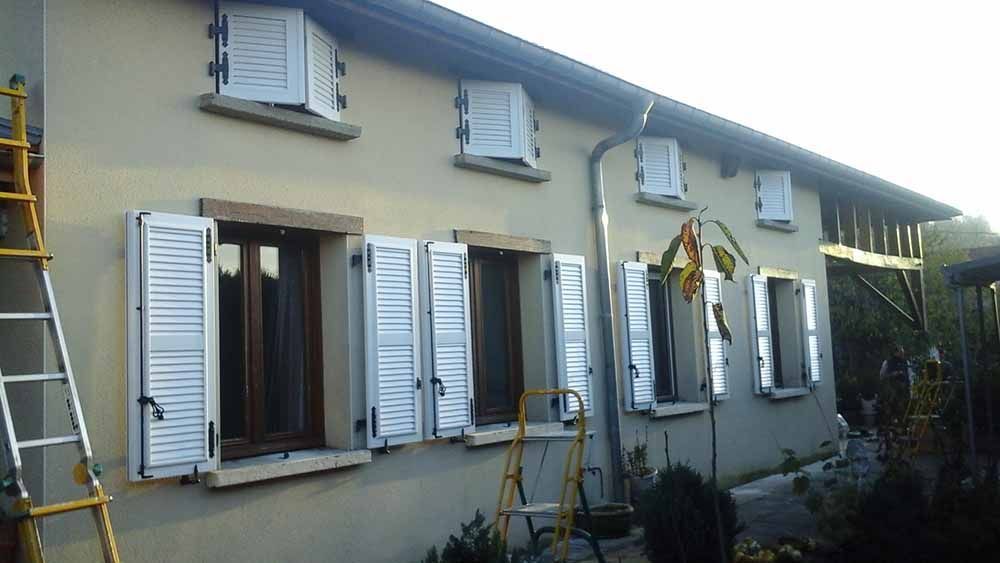 Extérieur de la maison avec des volets blancs et une échelle appuyée contre le mur gauche