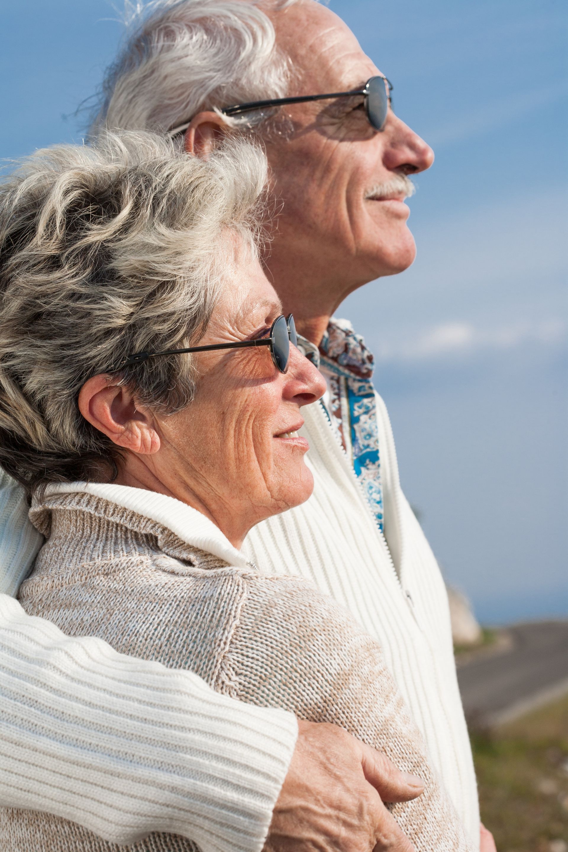 Un couple de personnes âgées, en pulls et lunettes de soleil, regarde le ciel.