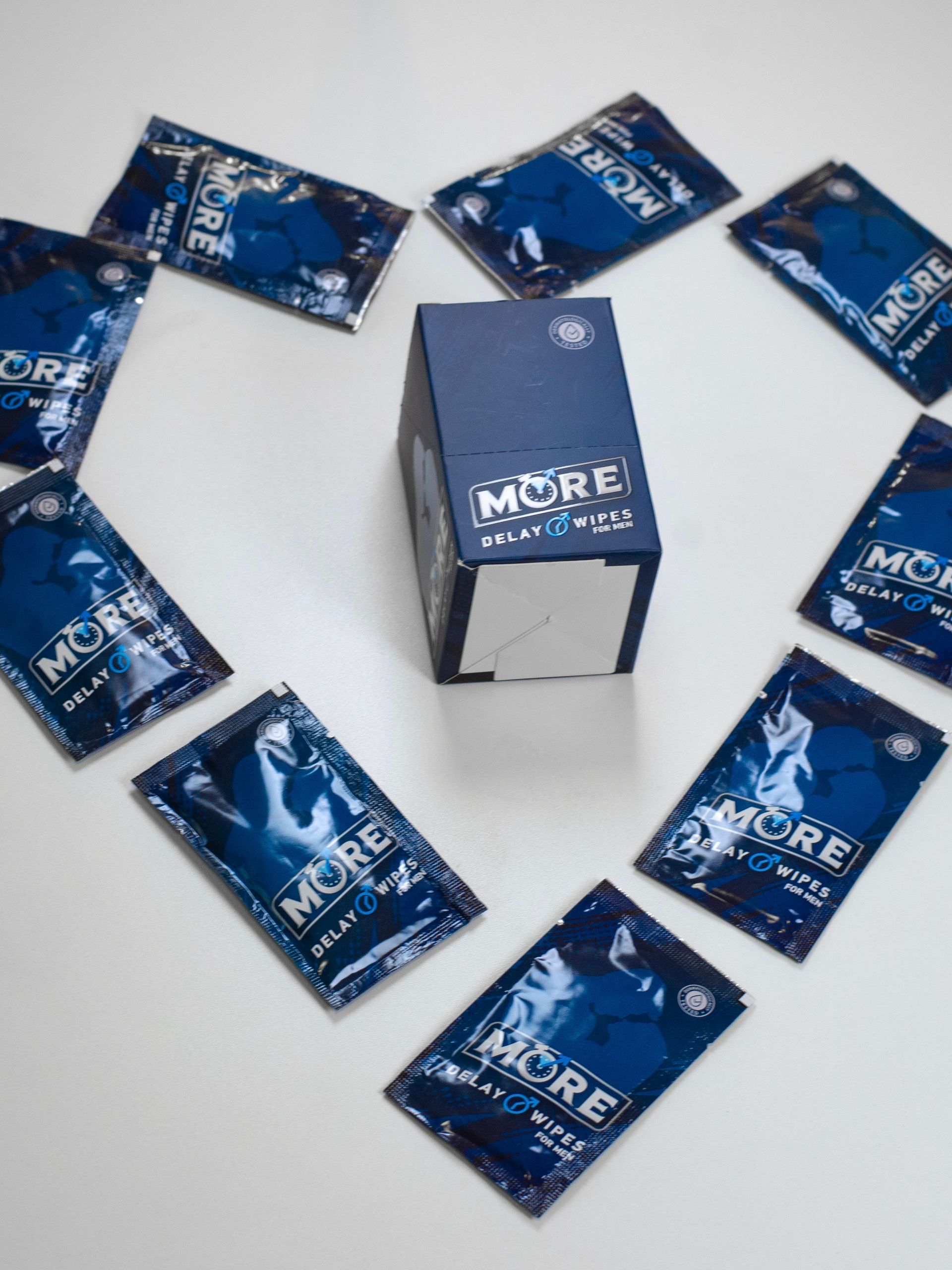 Schachtel und Päckchen mit „MORE“-Verzögerungstüchern in Herzform angeordnet. Blaue Verpackung.