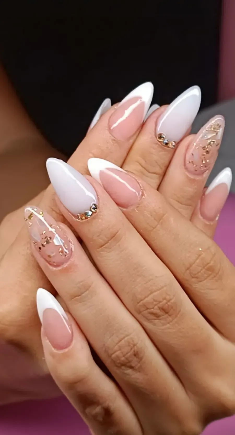 Primer plano de manos con uñas largas blancas y rosas brillantes.