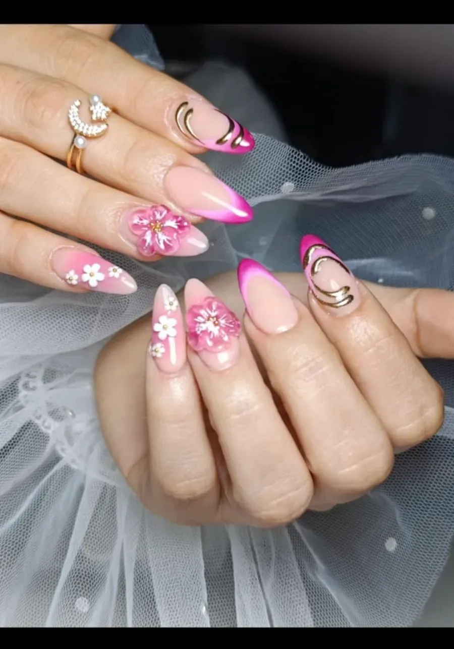 Manos con uñas decoradas en rosa y dorado sosteniendo una tela de tul blanco transparente.