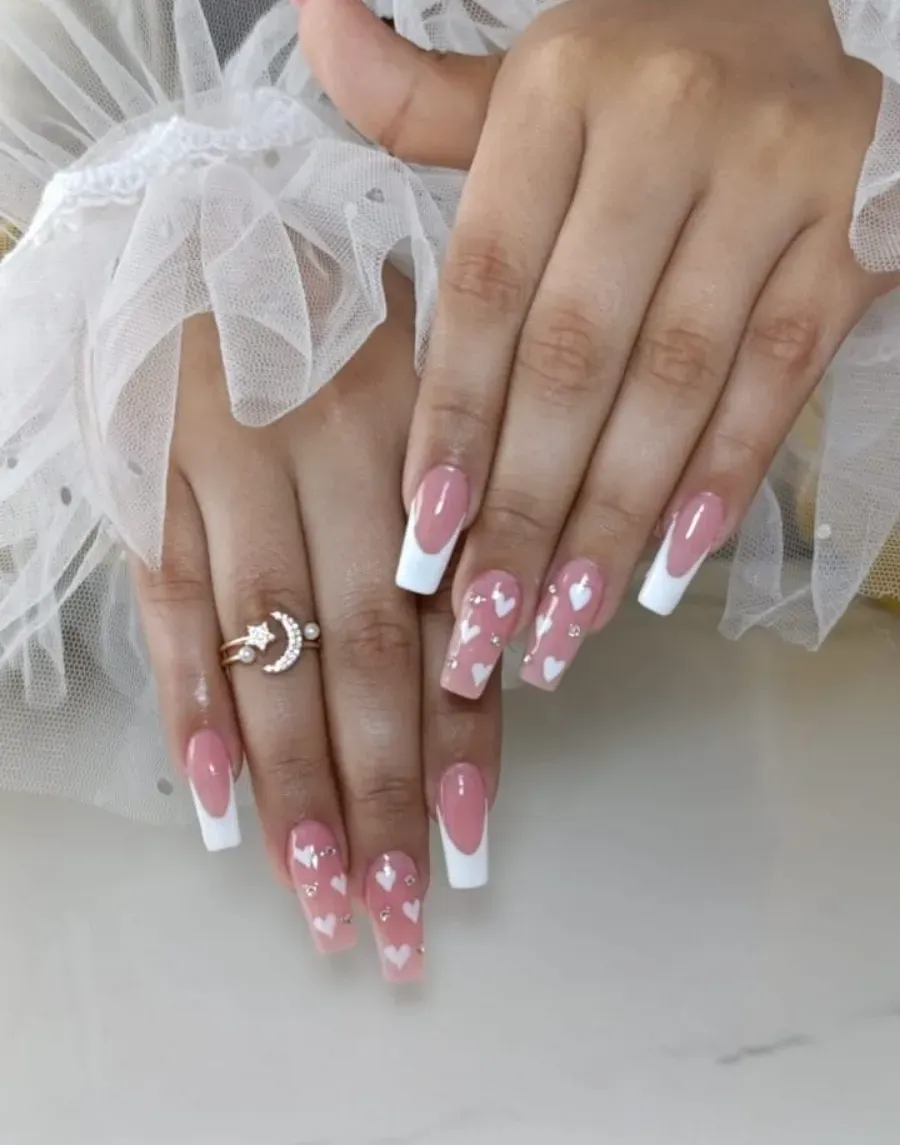 Manos con uñas largas de color rosa con punta francesa y decoración floral, descansando sobre tela de tul blanco.