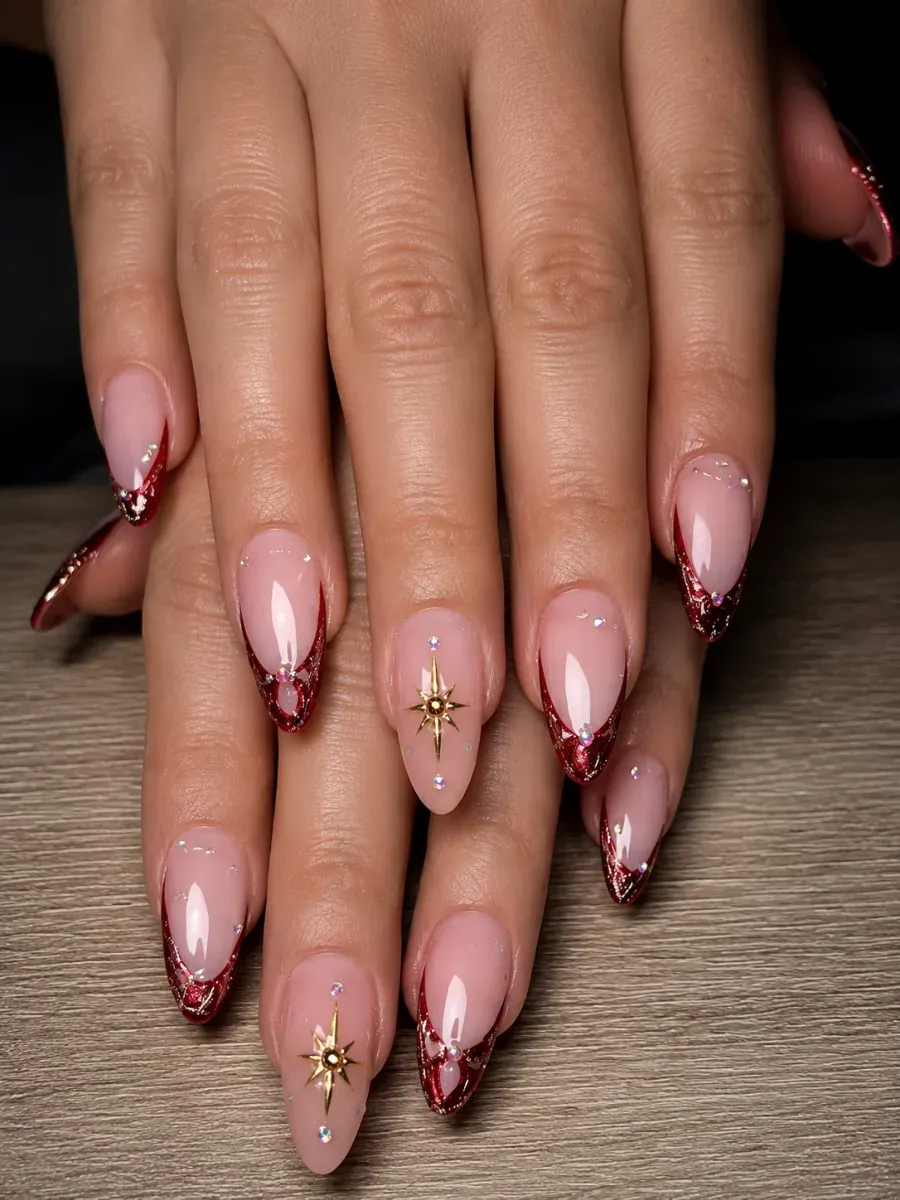 Mano con uñas largas de aguja rosa ombré y detalles dorados sobre un fondo oscuro.
