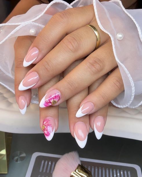 Manos con uñas pintadas de color rosa pálido y un anillo verde, apoyadas sobre una superficie clara.