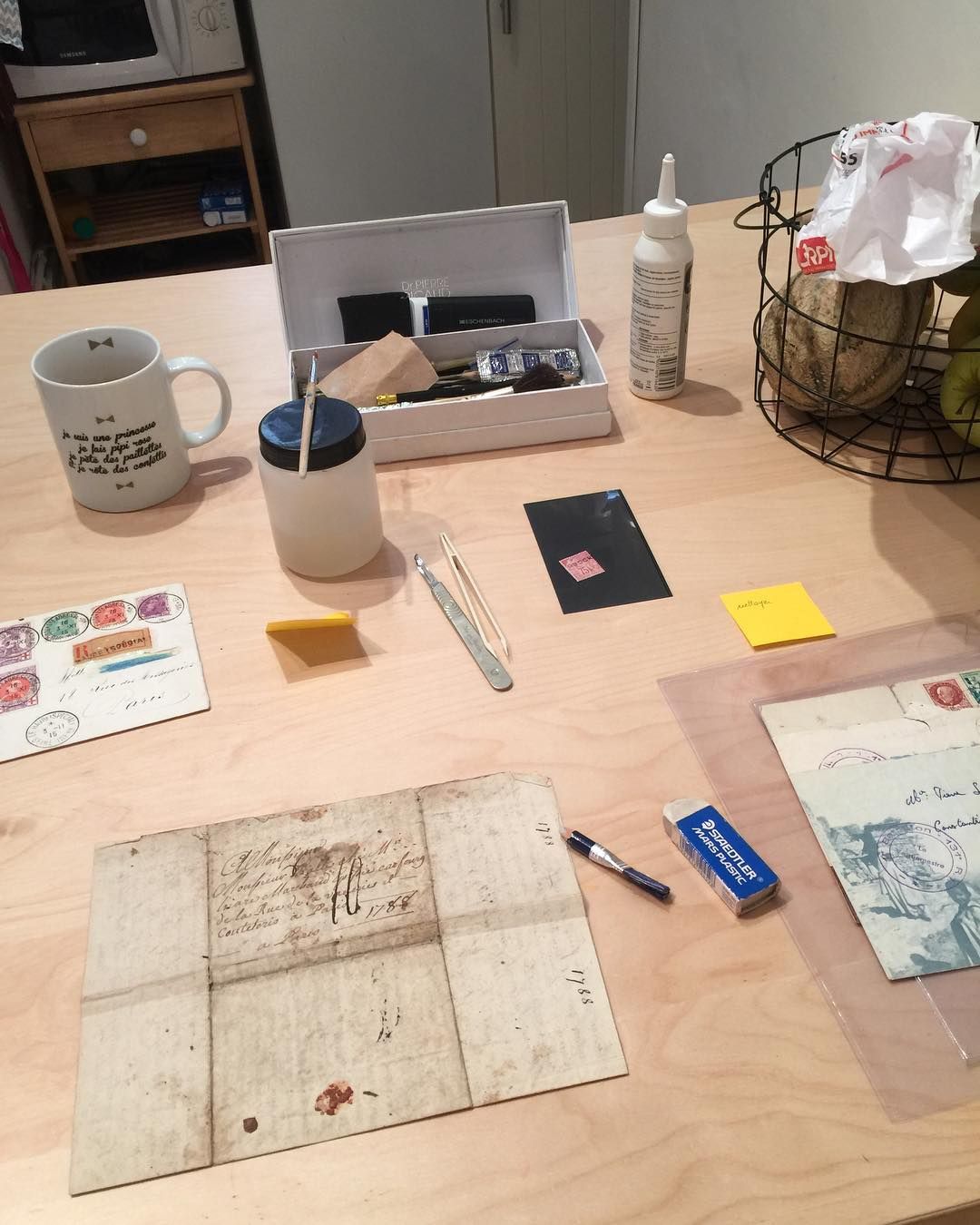 Table en bois avec une vieille lettre, des outils et une tasse ; préparation de documents anciens.