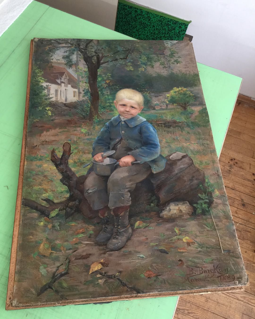 Garçon assis sur une bûche, tenant quelque chose dans une peinture d'une cour avec une maison.