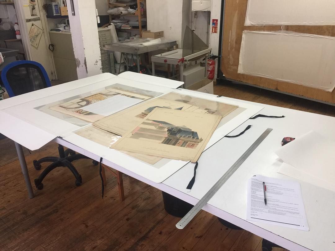 Une table de travail dans un studio avec de l'art et des outils.