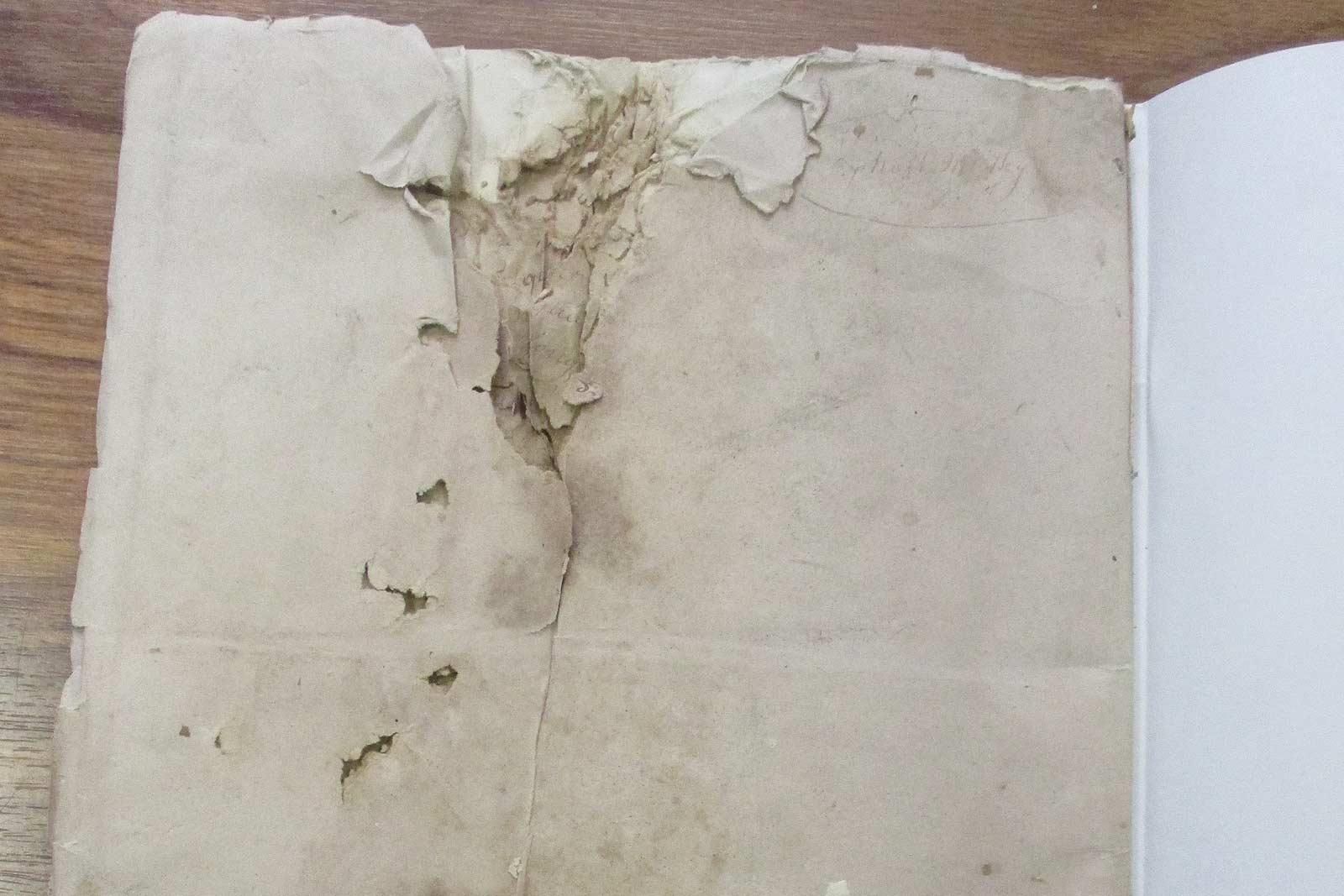 Papier beige endommagé, déchiré et usé à côté d'une page blanche et propre dans un cahier.