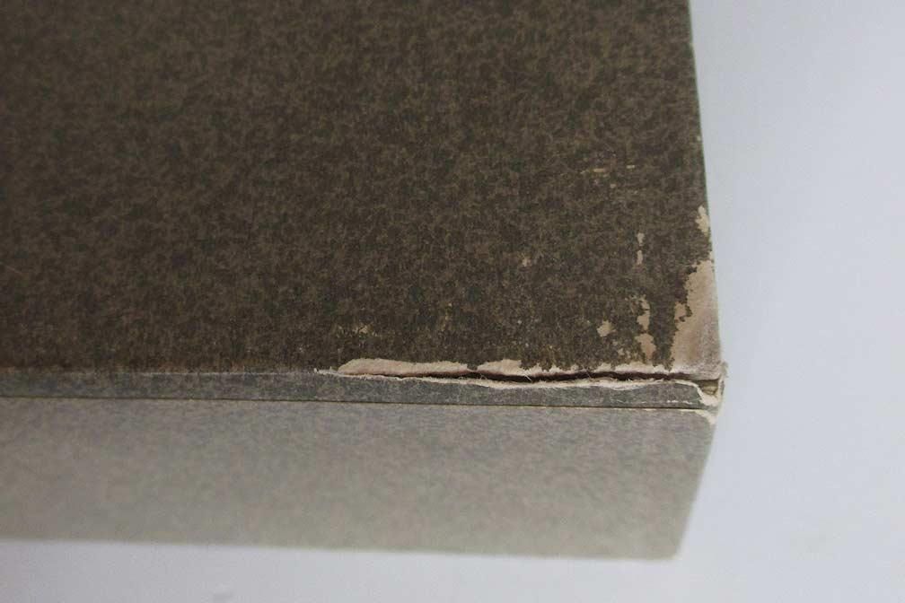 Gros plan sur un coin de boîte en carton endommagé, montrant des bords déchirés et une fissure le long de la couture.