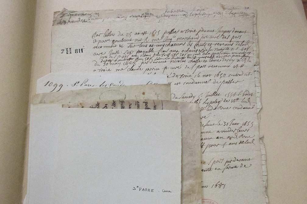 Documents manuscrits anciens sur papier vieilli. Vue partielle montrant du texte, probablement des documents historiques ou des lettres.