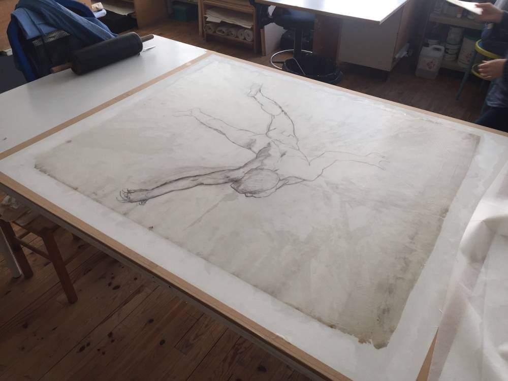 Croquis au crayon d'une figure allongée, encadrée sur une surface blanche, dans un atelier.