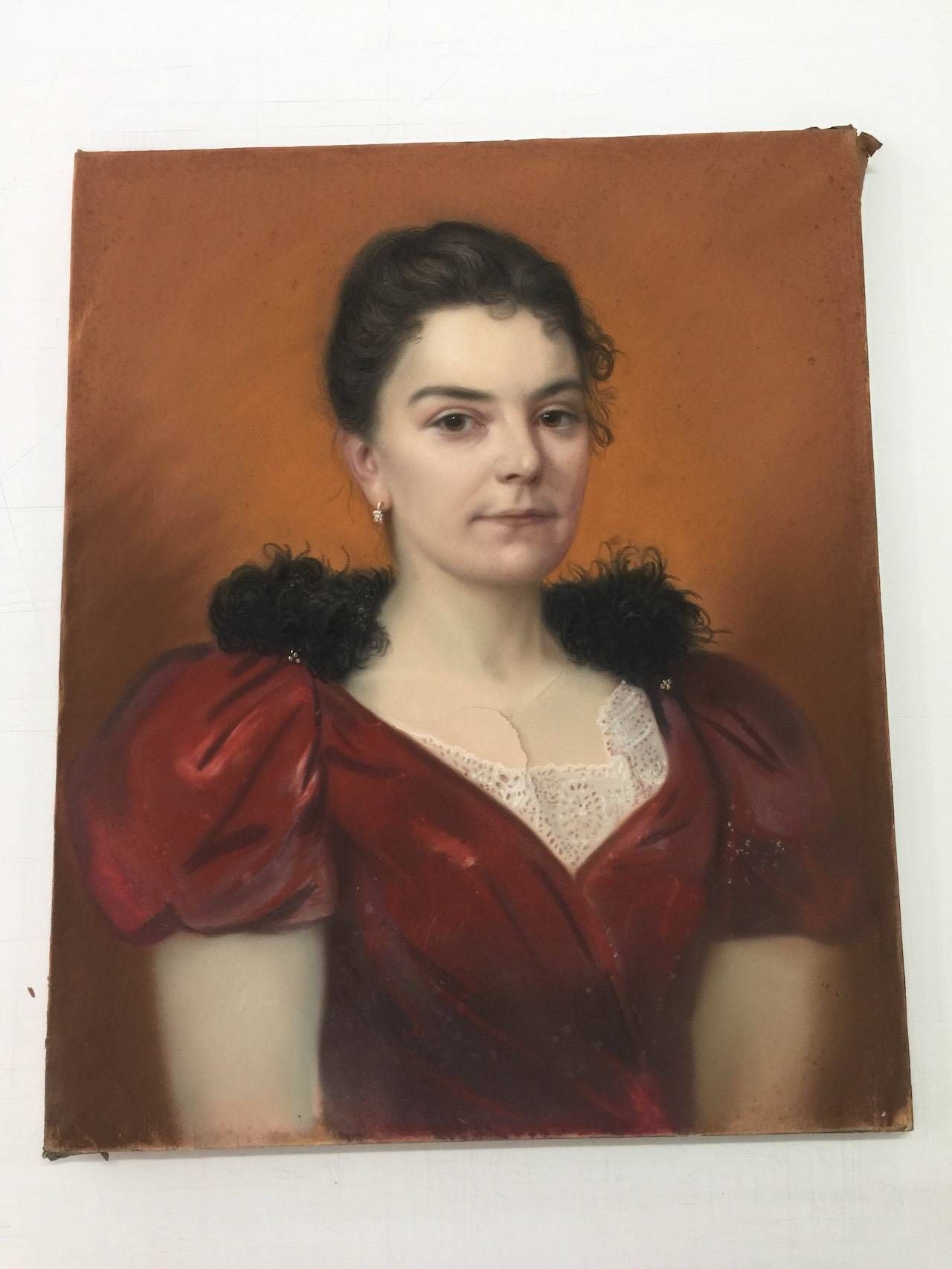 Portrait d'une femme portant une robe rouge à manches bouffantes et col en fourrure noire, sur fond orange.