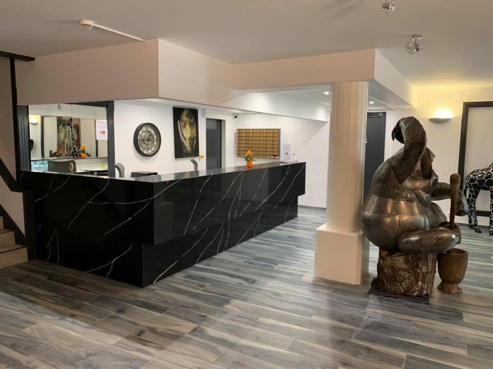 Hall d'hôtel avec réception en marbre noir et statue en bronze assise sur un sol imitation bois